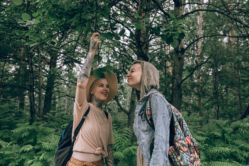 Two women happily exploring a beautiful green forest, enjoying nature and adventure.